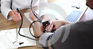 Cardiologist therapist doctor checking a man patient blood pressure at table