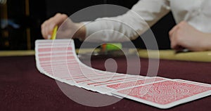 Cards and chips on the table in a casino. Close-up of hands.. Close-up of hands playing poker with chips on red table.