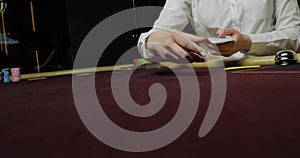 Cards and chips on the table in a casino. Close-up of hands.. Close-up of hands playing poker with chips on red table.