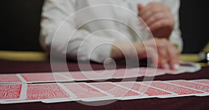 Cards and chips on the table in a casino. Close-up of hands.. Close-up of hands playing poker with chips on red table.