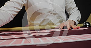 Cards and chips on the table in a casino. Close-up of hands.. Close-up of hands playing poker with chips on red table.