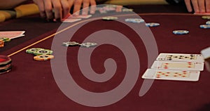 Cards and chips on the table in a casino. Close-up of hands.. Close-up of hands playing poker with chips on red table.