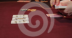 Cards and chips on the table in a casino. Close-up of hands.. Close-up of hands playing poker with chips on red table.