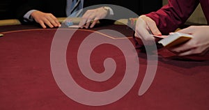 Cards and chips on the table in a casino. Close-up of hands.. Close-up of hands playing poker with chips on red table.