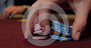 Cards and chips on the table in a casino. Close-up of hands.. Close-up of hands playing poker with chips on red table.