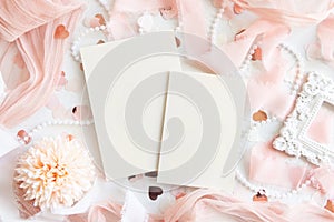 Cards near pink decorations, hearts and silk ribbons on white table top view, mockup