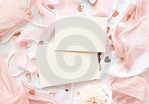 Cards near pink decorations, hearts and silk ribbons on white table top view, mockup