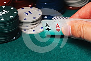 Cards with one pair of aces in the game of poker in the hands of a gambler on the background of chips