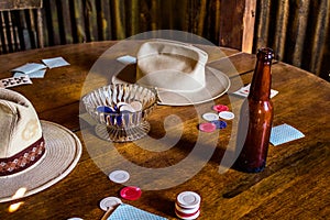 Cards, Poker Chips, Beer Bottle and Cowboy Hats on a Wooden Table