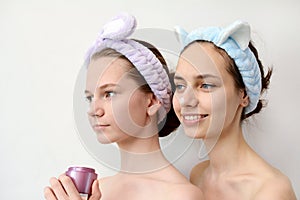 Care and cosmetics concept. Two young girls in the spa hold cream in their hands