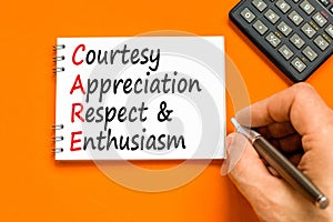 CARE symbol. Concept words CARE courtesy appreciation respect and enthusiasm on white note on beautiful orange background.