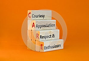 CARE symbol. Concept words CARE courtesy appreciation respect and enthusiasm on wooden block on beautiful orange background.