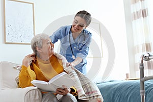 Care worker covering elderly woman with plaid in hospice