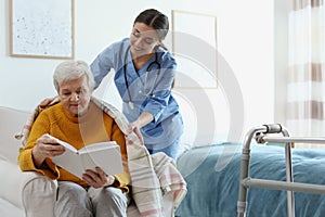 Care worker covering elderly woman with plaid in hospice