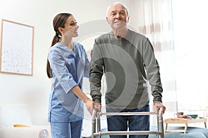 Care worker helping elderly man with walker in hospice