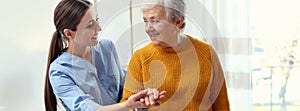 Care worker helping elderly woman to walk in geriatric hospice