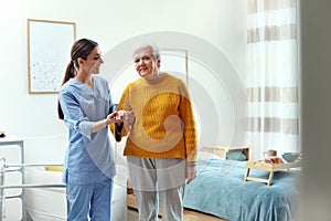 Care worker helping elderly woman to walk in hospice