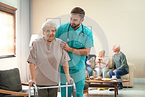 Care worker helping to elderly woman with walker in hospice