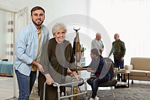 Care worker helping to elderly woman with walker in hospice