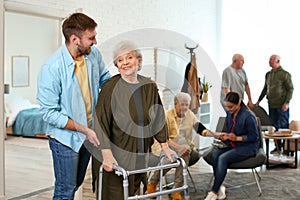 Care worker helping to woman with walker in geriatric hospice