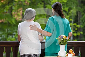 Care worker spending time with senior woman in nursing home care center