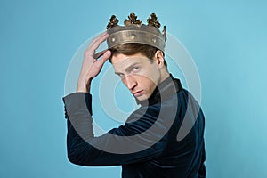 Career ambitions, concept. A young man in a suit puts a crown on his head,