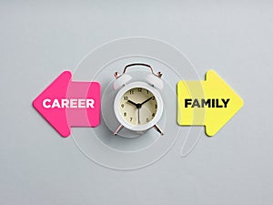 Career and family written on arrow note papers next to a clock. Dilemma between spending time for the career or family