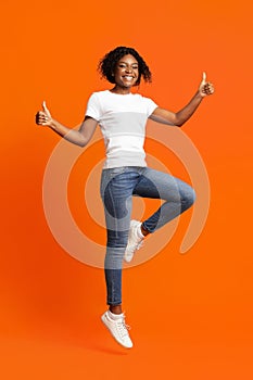 Carefree african-american lady jumping and showing thumb up