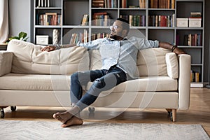 Carefree african man resting on sofa in cozy living room