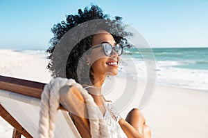 Carefree african woman relaxing on deck chair at tropical beach