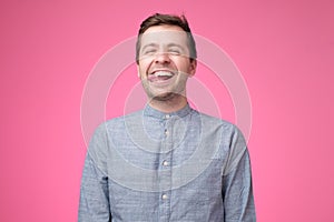 Carefree attractive guy in blue shirt showing tongue and making funny face