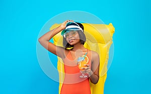 Carefree black lady in bikini lying on inflatable lilo with glass of tropical cocktail over blue background, panorama