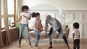 Carefree black parents and kids dancing together in living room