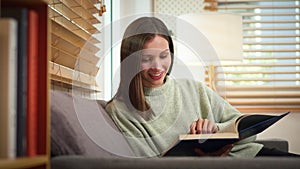 Carefree caucasian woman reading book, spending leisure time at home