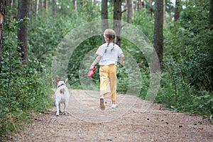 Carefree child with dog running on walkway in forest summer day