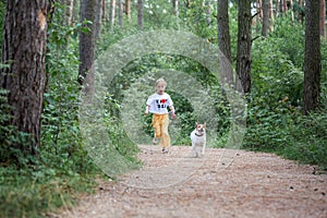 Carefree child with dog running on walkway in forest summer day. Happy girl running with pet