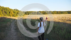 Carefree child going with toy plane along rural path. Happy small girl plays with airplane walking at country road. Cute