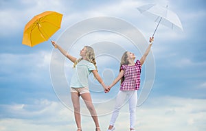 Carefree children outdoors. Girls friends with umbrellas cloudy sky background. Ready for any weather. Windy or rainy we