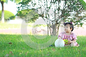Carefree Chinese baby girl play a ball and balloon on the lawn