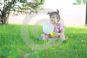 Carefree Chinese baby girl play a ball and balloon on the lawn