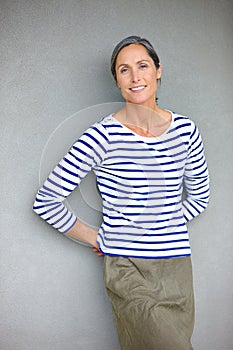 Carefree and confident. Portrait of an attractive mature woman in casualwear standing against a gray wall.