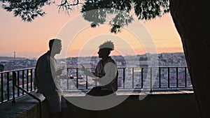 Carefree couple dating on evening viewpoint at sunset. Dark silhouettes people