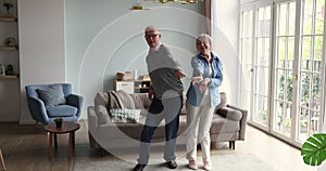 Carefree couple of older retirees dancing in living room