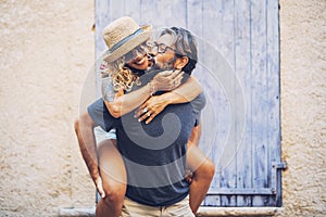 Carefree couple spending leisure time together outdoors, man giving piggyback ride to cheerful tattooed woman in sunglasses and