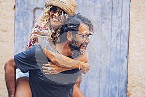 Carefree couple spending leisure time together outdoors, man giving piggyback ride to cheerful tattooed woman in sunglasses and