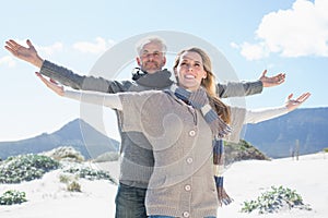 Carefree couple standing on the beach in warm clothing