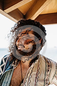 Carefree curly man relaxing on the beach during summer suny day