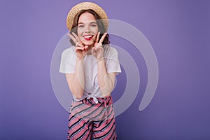 Carefree dark-haired girl posing with happy face expression on purple background. Stylish jocund wo