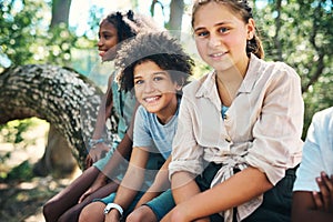 Carefree days at summer camp. a group of teenagers sitting on a tree trunk at summer camp.