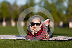 Carefree dreams. A little girl lies on the grass and smiles. Time for summer vacations and rest